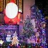 Christmas decorations with inflatable Santa, Christmas trees, and snowman lit up with colorful lights. Produktbild-Vorschau