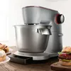 A Bosch kitchen mixer is shown on a wooden table, with baked goods and a hamburger nearby. Anteprima dell’immagine prodotto