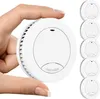 A hand is holding a white smoke detector, with a stack of five more smoke detectors visible on the right side of the image. Podgląd zdjęcia produktu