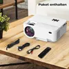 A white mini projector and its accessories are laid out on a wooden table. Produktbild-Vorschau