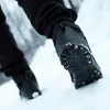 A close-up shot of a person's feet wearing winter boots in the snow. Produktbild-Vorschau