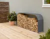 A metal firewood rack filled with logs sits on a wooden deck next to a potted plant and a woven screen. Produktbild-Vorschau