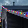 Colorful Christmas lights are strung along the roofline of a house. Produktbild-Vorschau