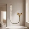 A luxurious bathroom with a bathtub and a gold shower system, showing water flowing from the showerhead. Náhled obrázku produktu
