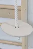 A close-up of a wooden disc swing attached to a rope, hanging from a wooden wall-mounted gym structure. Podgląd zdjęcia produktu