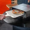 A person is using a pizza peel to slide a pizza into a pizza oven. Podgląd zdjęcia produktu