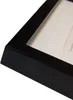 A close-up view of the corner of a black picture frame with a white matting inside. Náhled obrázku produktu