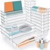 A collection of clear plastic drawer organizers filled with various items like makeup brushes, jars, and colorful rolls. Náhled obrázku produktu