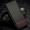 A carbon fiber phone case with a red accent strip is displayed on a textured dark background, with a spherical object also covered in carbon fiber texture behind it. Produktbild-Vorschau