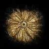 A close-up, top-down view of a solar-powered hanging lamp with a dandelion-like structure made of thin, golden wires. Produktbild-Vorschau