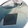 A close-up of a blue glass perfume bottle with red text on it. Anteprima dell’immagine prodotto