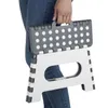 A person's lower body wearing jeans is shown holding a folded plastic step stool. Podgląd zdjęcia produktu