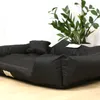 A black dog bed is shown in a room with a plant in the background. Anteprima dell’immagine prodotto