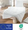 A white duvet and pillow set on a wooden bed frame, with a vase and lamp in the background. Produktbild-Vorschau