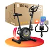 A black exercise bike is shown on a colorful circular platform, with a cardboard box in the background. Produktbild-Vorschau