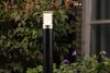 A black garden bollard light with a silver and white top is situated in a garden setting, surrounded by green foliage and purple flowers. Produktbild-Vorschau