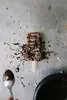A chocolate popsicle drizzled with chocolate sauce and sprinkled with nuts, on a metallic surface. Anteprima dell’immagine prodotto