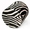A cylindrical pouffe with a zebra print pattern is shown against a white background. Produktbild-Vorschau