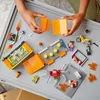 A child's hands assembling LEGO City Stunt-Park pieces on a gray surface. Podgląd zdjęcia produktu