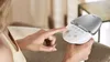 A person's hand is shown interacting with a Philips Lumea Prestige IPL hair removal device. Náhled obrázku produktu