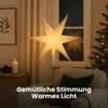 A paper star lantern hangs in a window, casting a warm glow. A Christmas tree and a candle are also visible, creating a cozy atmosphere. Podgląd zdjęcia produktu