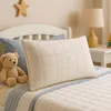 A child's bed with a pillow, teddy bear, and a lamp on a nightstand. Náhled obrázku produktu
