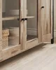 Close-up of the lower section of a wooden sideboard with glass doors, showing stacked plates and a woven basket inside. Náhled obrázku produktu