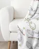 A white blanket with a Harry Potter-themed print of Hedwig the owl is draped over the arm of a white armchair. Produktbild-Vorschau