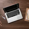 A laptop and its accessories are laid out on a wooden desk. Produktbild-Vorschau