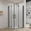 A black framed glass shower enclosure with double doors is shown in a bathroom setting with white brick walls and a wooden floor.