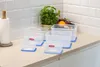 A set of clear plastic food storage containers with blue lids are arranged on a kitchen countertop. Náhled obrázku produktu