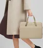 A person is holding a beige laptop bag. Náhľad obrázku produktu