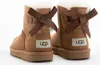 A close-up rear view of two brown Ugg boots with white fur lining and brown bows on the back. Produktbild-Vorschau