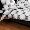 A close-up view of a bed with white bedding featuring a geometric pattern in gray and black. Produktbild-Vorschau