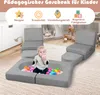 A baby playing with colorful balls in a soft play area with modular foam furniture. Voir les images du produit