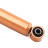 A close-up, side view of a shock absorber with a copper-colored body and a black rubber bushing within a metal housing. Náhled obrázku produktu