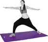 A woman is performing a yoga pose on a purple yoga mat. Podgląd zdjęcia produktu