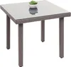 A square poly-rattan garden table with a glass top and a small potted plant on it, isolated on a white background. Podgląd zdjęcia produktu