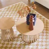 Two round coffee tables of different sizes are placed on a checkered rug. One table has a vase with dried flowers and a decorative object on it. Produktbild-Vorschau