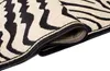 A close-up view of a rolled-up rug with a zebra pattern. Produktbild-Vorschau
