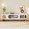 A white TV cabinet with decorative elements and items on top, set against a light-colored wall and a checkered rug. Anteprima dell’immagine prodotto