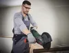 A man is using an angle grinder to cut a metal pipe. Produktbild-Vorschau