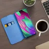A smartphone with a blue flip case, a cup of coffee, and a laptop on a wooden desk. Voir les images du produit