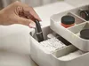 A hand is placing a lipstick into a makeup organizer. Náhled obrázku produktu