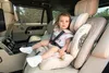 A young child is sitting in a car seat inside a luxury vehicle. Voir les images du produit