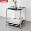 A small, two-tiered side table with a black top and shelf, supported by a chrome metal frame. It is decorated with books, a candle, a small plant, and towels. Anteprima dell’immagine prodotto