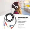 A woman wearing headphones leans against a wall, with a close-up of an audiometer headset cable in the foreground. Podgląd zdjęcia produktu