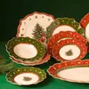 A collection of Christmas-themed dinner plates and bowls arranged on a green surface. Anteprima dell’immagine prodotto