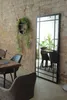 A dining area with a large mirror reflecting chairs and plants. Produktbild-Vorschau