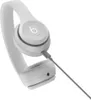 A pair of white Beats Solo 4 headphones with a gray cable, shown from a side angle against a white background. Produktbild-Vorschau